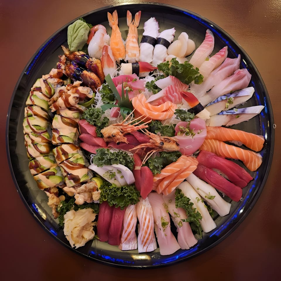 A large platter of Tsunami Sushi's assorted sushi and sashimi, including rolls, nigiri, and raw fish.